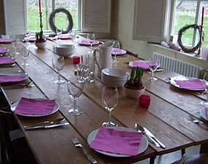 Gezellige eetkamer in Huisje in Winterswijk Woold, vakantiehuis in de Achterhoek, Gelderland, met een grote houten tafel en kleurrijke accenten.