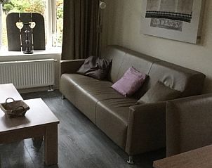 Stilvolle Sitzecke im Chalet Vlinderhof, Beekbergen, Veluwe mit bequemem Sofa und dekorativen Elementen.