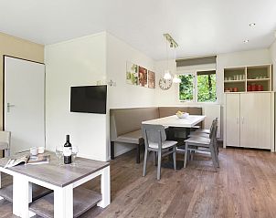 Comfortabele zithoek in Heideheuvel bungalow, Beekbergen, Veluwe, met uitzicht op groen.