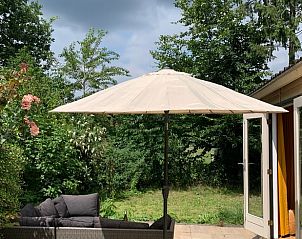Zonnig terras met parasol bij Vakantiehuis in Koudhoorn, Veluwe, omgeven door natuur.