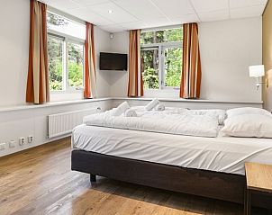 Ruime slaapkamer in Heideheuvel bungalow, Beekbergen, Veluwe met grote ramen.