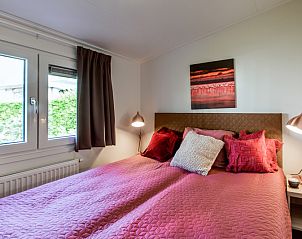 Gemtliches Schlafzimmer im Ferienhaus Rialto fr 6 Personen, Beekbergen, Veluwe. Bequemes Bett mit bunten Kissen und Blick auf die Natur.