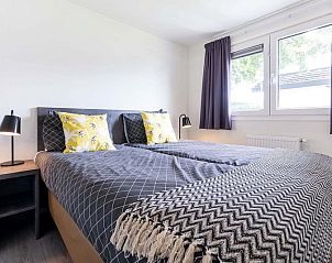 Sfeervolle slaapkamer in Parel 5 personen Wellness vakantiehuis, Ede, Veluwe, met comfortabel bed en natuurlijk licht door grote ramen.