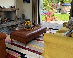 Woonkamer met open haard en toegang tot tuin in Vakantiehuis in Ede, Veluwe, Gelderland.