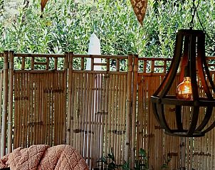 Gezellige veranda van Vakantiehuis in Emst, Veluwe, Gelderland met sfeervolle verlichting en natuurlijke bamboe omheining.