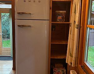 Cozy kitchen corner in Holiday cottage in Emst, Veluwe, Gelderland with retro fridge and view of green surroundings.