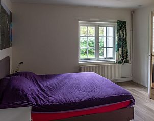 Attractive bedroom in Holiday Home in Emst, located in the Veluwe in Gelderland, with views of green nature through a large window.