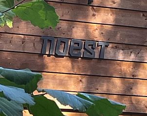 Houten gevel van Vakantiehuis in Emst, Veluwe, Gelderland, met moderne letters en omgeven door groene natuur.