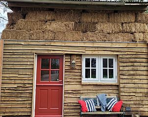 Rustieke buitenkant van Huisje in Emst met strobedekking, een uniek verblijf in Veluwe, Gelderland.