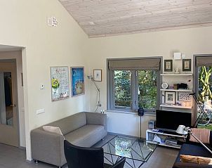 Cozy living room in Cottage in Emst, Veluwe, Gelderland, overlooking the green garden and modern furnishings for a relaxing stay.