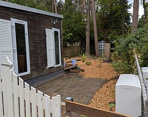 Vacation cottage in Emst in the Veluwe, Gelderland, with cozy porch and wooded area for a relaxing stay.