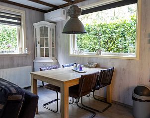 Cozy dining area in Cottage in Emst, cottage in Veluwe, Gelderland, overlooking green garden and stylish decor.