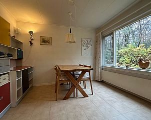 Cozy dining area in Holiday Home in Emst, Veluwe, overlooking the green nature of Gelderland.