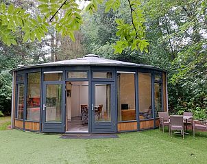 Round vacation home in Ermelo, Veluwe, Gelderland surrounded by greenery. Cozy accommodation with spacious windows and terrace for a relaxing stay.
