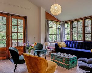 Cozy living room of Huisje in Ermelo, vacation home in Veluwe, Gelderland, overlooking the green nature through large windows.