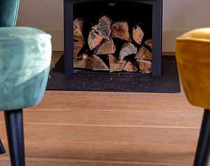 Cozy indoor area of Cottage in Ermelo in Veluwe, Gelderland, with a cozy fireplace and comfortable chairs.