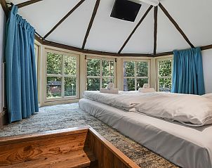 Comfortabele slaapkamer in Miggelenberg boomhut, met grote ramen en veel lichtinval.