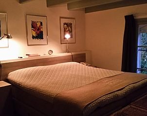 Gezellige slaapkamer van Huisje in Terwolde, vakantiehuis op de Veluwe, met kunstwerken en uitzicht op de natuur.