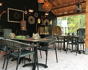 Overdekt terras met zitplaatsen bij Vakantiehuisje in Garderen.