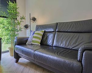 Stijlvolle zwarte leren bank in De Veluwse houtduif, Garderen, Veluwe met uitzicht op de tuin.