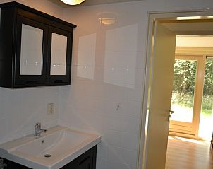 Badkamer in Vakantiehuis in Elspeet met moderne wastafel en toegang tot buiten.