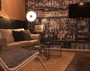 Sfeervolle woonkamer in Vakantiehuis in 't Harde, Veluwe, met unieke wanddecoratie.