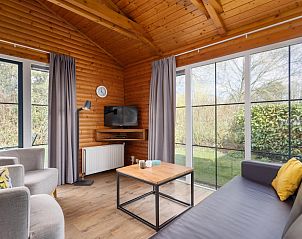 Gezellige woonkamer van Loghome 6 bungalow in Putten, Veluwe, met houten interieur en uitzicht op de groene tuin.