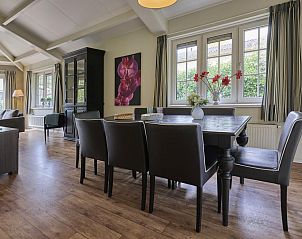 Cozy dining room in vacation home Heidepracht, Putten, Veluwe with large windows and stylish furnishings.
