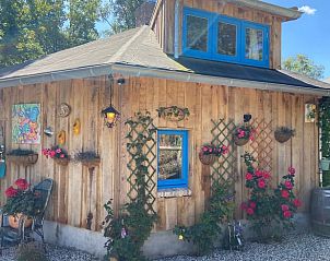 Charming wooden vacation home Cottage in Voorthuizen in Veluwe, Gelderland with colorful flowers on the facade.