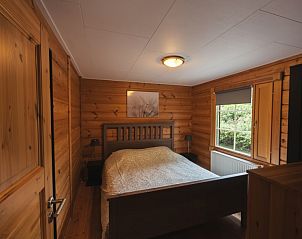Sfeervolle slaapkamer in Vakantiehuis de Blokhut, Voorthuizen, Veluwe met houten interieur en uitzicht op de natuur.