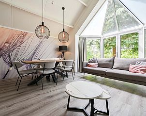 Lichte woonkamer in vakantiehuis Vaassen, Veluwe, met uitzicht op de natuur.