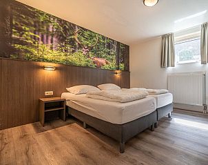 Slaapkamer met tweepersoonsbed in vakantiehuis Vaassen, Veluwe, met bosdecor.