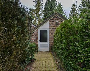 Zijaanzicht van vrijstaande woning in Vaassen, Veluwe, met groene begroeiing.