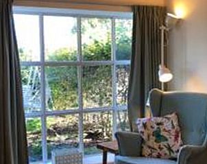 Gezellige leeshoek in vakantiehuis in Hulshorst met uitzicht op de tuin, Veluwe, Gelderland.