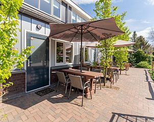 Terras van vakantiehuis Koolmees in Hulshorst, Veluwe met tafels en parasols voor ontspannen buiten zitten.