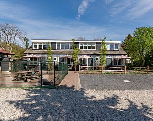 Vooraanzicht van vakantiehuis Zwarte Mees, Hulshorst. Ruime buitenruimte met omheind terras en groene omgeving.