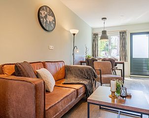 Comfortabele zithoek in vakantiehuis Kuifmees, Hulshorst, Veluwe met leren bank en decoratie.