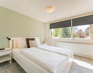 Lichte slaapkamer in vakantiehuis Kuifmees, Hulshorst, Veluwe met groot raam en uitzicht op natuur.