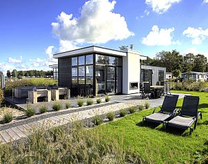 Moderne buitenkant van Vakantiehuis Cube Exclusif Waterfront 4 in Hulshorst, Veluwe, met terras en ligstoelen.