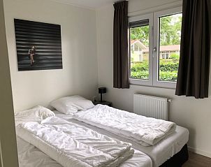 Comfortabele slaapkamer in Vakantiehuis Superieur 6, Hulshorst, Veluwe, met uitzicht op de natuur.