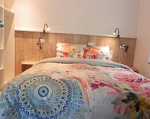 Gemtliches Schlafzimmer im Ferienhaus in Otterlo, Veluwe, mit farbenfrohem Bettzeug und stimmungsvoller Beleuchtung, ideal fr einen entspannten Aufenthalt.