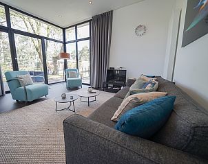 Gezellige woonkamer in Chalet in Otterlo, Veluwe met veel lichtinval en comfortabele zitplaatsen.