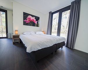 Ruime slaapkamer in Chalet in Otterlo, Veluwe, met comfortabele bedden en uitzicht op de natuur.