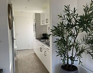 Doorkijk naar keuken in Chalet in Otterlo, Veluwe, met moderne apparatuur en stijlvolle inrichting.