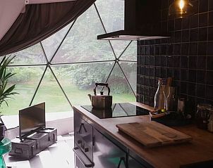 Stijlvolle keuken in het Huisje in Otterlo, vakantiehuis op de Veluwe, Gelderland met uitzicht op de groene natuur door glazen wand.