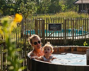 Gezin geniet van hot tub in de tuin van Huisje in Oosterwolde, Veluwe, Gelderland.