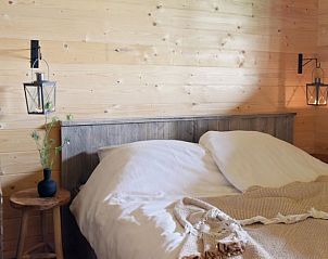 Knusse slaapkamer in vakantiehuis Oosterwolde, Veluwe, met houten wanden en sfeervolle verlichting.