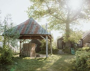 Schuur met rustieke uitstraling bij vakantiehuis Oosterwolde, Veluwe, omgeven door groen.