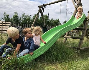 Kinderen spelen op glijbaan bij Huisje in Oosterwolde Gelderland, plezier voor het hele gezin.