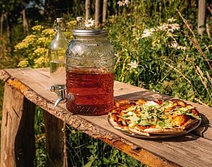 Pizza en drankjes op houten tafel bij vakantiehuis Oosterwolde Gelderland, genieten in de natuur.